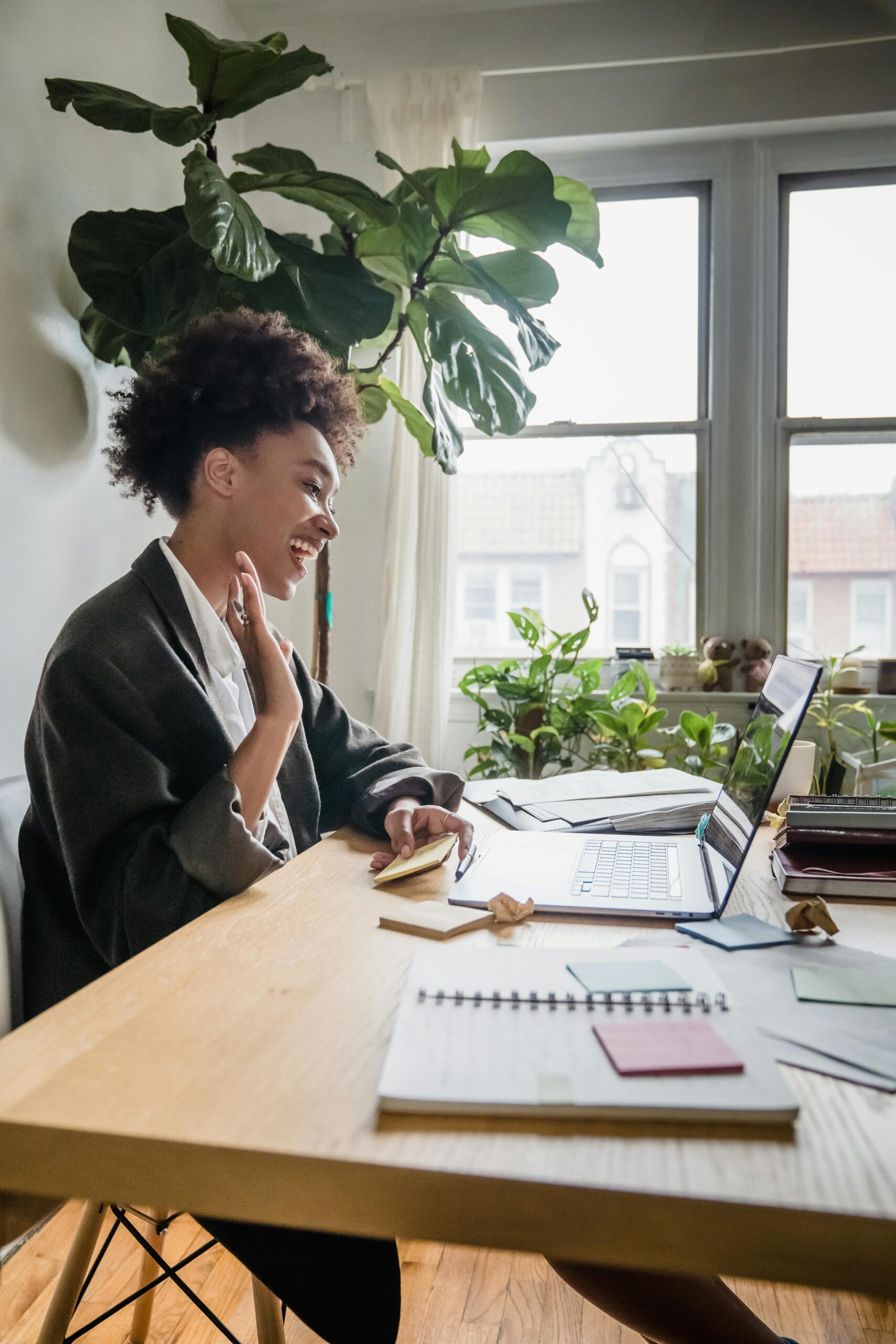 smiling female working at the office using laptop in the middle of a video call and waving her hand